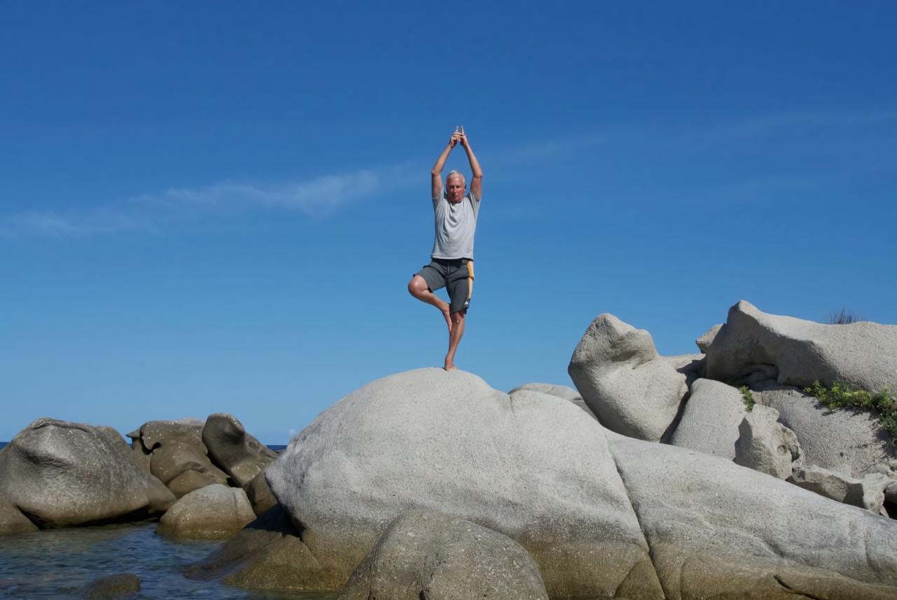 Werner Haas bei der Yogaübung 'Baum' am Meer